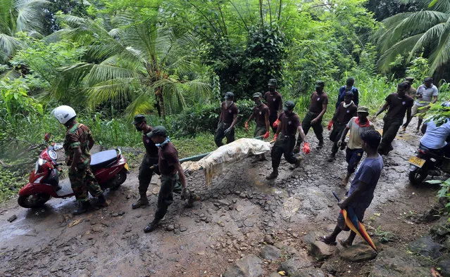 Sri Lankan army soldiers carry the body of a victim of a mudslide in Kiribathgala village in Ratnapura district, Sri Lanka, Monday, May 29, 2017. Kiribathgala Hill known for its gems and precious stones came crashing down last Thursday covering eight houses with their 18 inhabitants. Soldiers have recovered more than a dozen dead bodies on Monday. (Photo by Eranga Jayawardena/AP Photo)