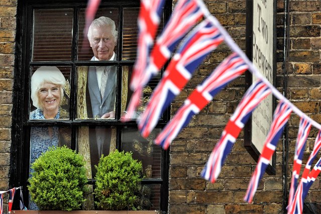 Cardboards picturing Britain's Camilla, Queen Consort (L) and Britain's King Charles III are displayed on the window of a pub in a street adorn with Union Jack flags, in Windsor, on May 2, 2023, ahead of the coronation ceremony of Charles III and his wife, Camilla, as King and Queen of the United Kingdom and Commonwealth Realm nations, on May 6, 2023. (Photo by Adrian Dennis/AFP Photo)