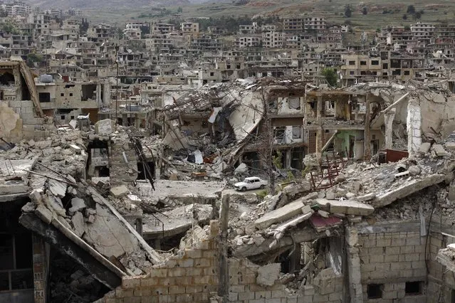 In this May 18, 2017 photo, a car passes by damaged streets at the mountain resort town of Zabadani in the Damascus countryside, Syria. Once a popular summer resort famed for its fruit trees and favored by tourists from rich Gulf Arab countries, the Damascus suburb town of Zabadani is now a deserted, endless vista of pulverized buildings after  thousands of rebels were driven out along with the town’s original inhabitants. (Photo by Hassan Ammar/AP Photo)
