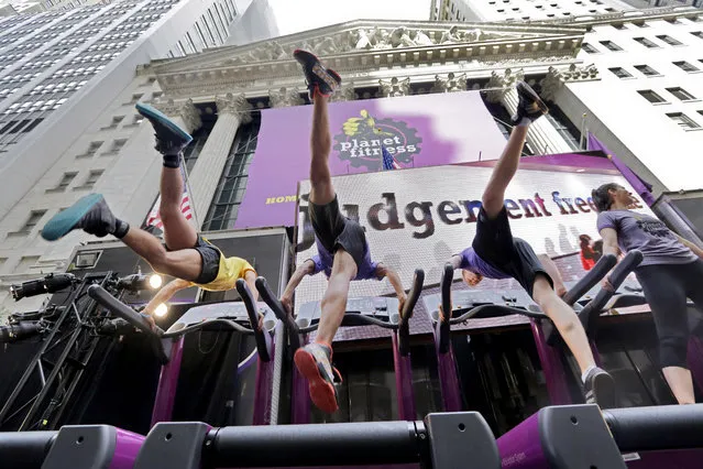 Planet Fitness dancers perform on treadmills outside the New York Stock Exchange after the company's IPO, Thursday, August 6, 2015. U.S. stocks edged modestly lower in early trading as investors look over the latest deal and earnings news. Sliding oil prices pulled stocks in energy companies lower. (Photo by Richard Drew/AP Photo)