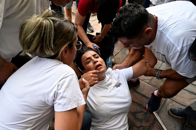 Bank customers help a woman who fainted during a protest organized by Depositors' Outcry, a group campaigning for the rights of depositors, in the Dora area, northern Beirut, Lebanon, 29 August 2024. Bank customers demand they be allowed to withdraw their savings, which have been blocked as a result of the ongoing economic crisis in the country, as the Lebanese pound has lost about 95 percent of its value against the US dollar. The currency was trading on the parallel market at 89,500 against the dollar on 29 August, more than five times the 15,000 official rate. (Photo by Wael Hamzeh/EPA/EFE)