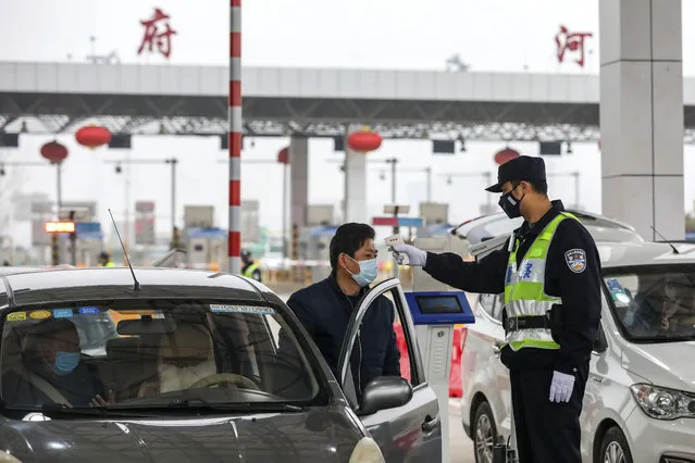 A policeman uses a digital thermometer to take a driver's temperature at a checkpoint at a highway toll gate in Wuhan in central China's Hubei Province, Thursday, January 23, 2020. China closed off a city of more than 11 million people Thursday in an unprecedented effort to try to contain a deadly new viral illness that has sickened hundreds and spread to other cities and countries amid the Lunar New Year travel rush. (Photo by Chinatopix via AP Photo)