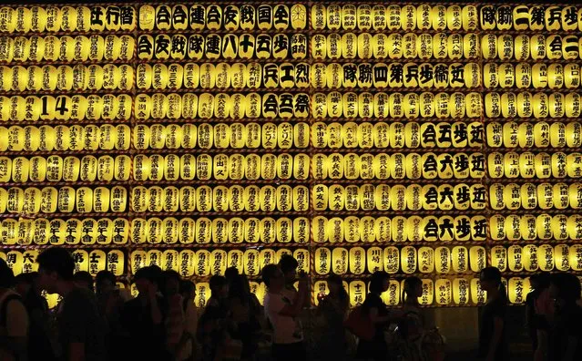 People walk in front of paper lanterns during the annual Mitama Festival at the Yasukuni Shrine in Tokyo July 13, 2014. Over 30,000 lanterns light up the precincts of the shrine, where more than 2.4 million war dead are enshrined, during the four-day festival. The festival goes on till July 16. (Photo by Yuya Shino/Reuters)