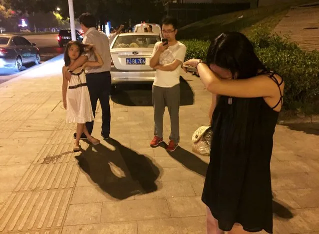People react near a street after a blast at Binhai new district, in Tianjin municipality, China, August 12, 2015. A huge explosion hit an industrial area in the northeastern Chinese city of Tianjin late on Wednesday evening, triggering a blast wave felt several kilometres away and injuring at least 50 people, domestic media reported. (Photo by Reuters/Stringer)