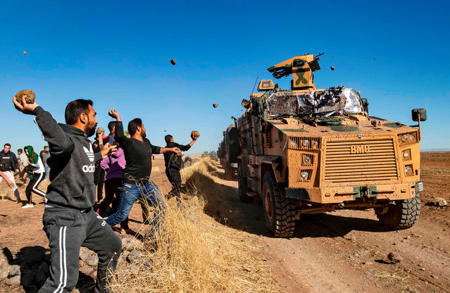 Kurdish demonstrators hurl rocks at a Turkish military vehicle on November 8, 2019, during a joint Turkish-Russian patrol near the town of Al-Muabbadah in the northeastern part of Hassakah on the Syrian border with Turkey. (Photo by Delil Souleiman/AFP Photo)