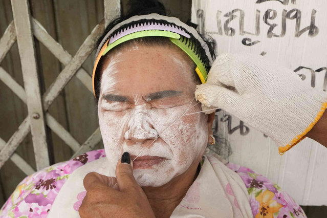 A roadside beautician uses a threading technique to remove hair from a customer in Bangkok, Thailand, Friday, September 27, 2024. (Photo by Sakchai Lalit/AP Photo)