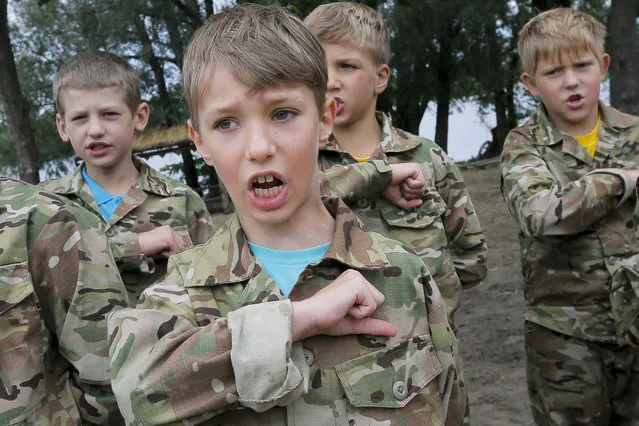 In this photo taken on Friday, July 14, 2017, students at a paramilitary camp for children sing the Ukrainian national anthem before the start of exercises outside Kiev, Ukraine. (Photo by Efrem Lukatsky/AP Photo)