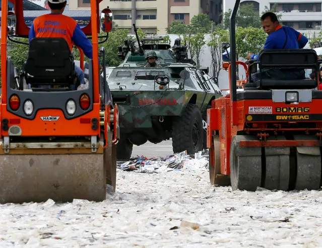 A Philippine National Police armored personnel carrier runs over fake DVD's while road rollers do the same to fake sunglasses during a symbolic destruction of counterfeit goods at Camp Crame Monday, July 4, 2016 in suburban Quezon city, northeast of Manila, Philippines. The symbolic destruction was in compliance with the Government's fight against counterfeiting and piracy and to drive the message to the public of the dangers of substandard goods to health and safety. The Intellectual Property Office has seized about $60-million US dollars worth of fake goods in the first five months of the year. (Photo by Bullit Marquez/AP Photo)