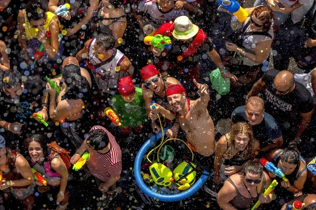 People take part during the annual water fight in the streets of the Vallecas neighborhood of Madrid, Spain, Sunday, July 17, 2022. (Photo by Manu Fernandez/AP Photo)