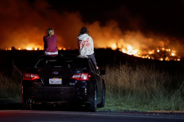 Lily Moore and Megan Panighetti watch the Park Fire burning as they sit on top of a car in Chico, California,  on July 25, 2024. (Photo by Fred Greaves/Reuters)