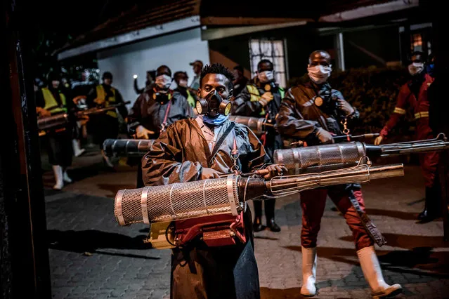 Members of a privately-funded NGO working with county officials wearing protective carry their gear on April 15, 2020, during the dusk-to-dawn curfew imposed by the Kenyan Government, before carrying out an operation aimed to fumigate and disinfect the streets and the stalls at Parklands City Park Market in Nairobi to help curb the spread of the COVID-19 coronavirus. With a current official number of 225 confirmed coronavirus cases, Kenya has so far cordoned off the capital and parts of its coastline and imposed a curfew and other social distancing measures as part of the country efforts to control the spread of the virus. (Photo by Luis Tato/AFP Photo)