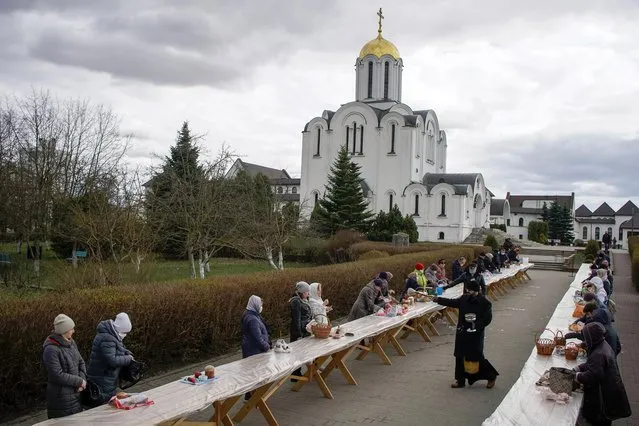 An Orthodox priest sprinkles holy water on believers and their “paskha” cakes, eggs and other food on the eve of the Orthodox Easter, amid the coronavirus disease (COVID-19) outbreak in Minsk, Belarus on April 18, 2020. (Photo by Vasily Fedosenko/Reuters)