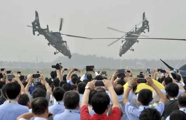 Spectators use their mobile phones to take pictures and videos as Z-19 helicopters of the People's Liberation Army (PLA) perform during an aerobatic display at the China Helicopter Exposition in Tianjin, September 9, 2015. (Photo by Reuters/China Daily)