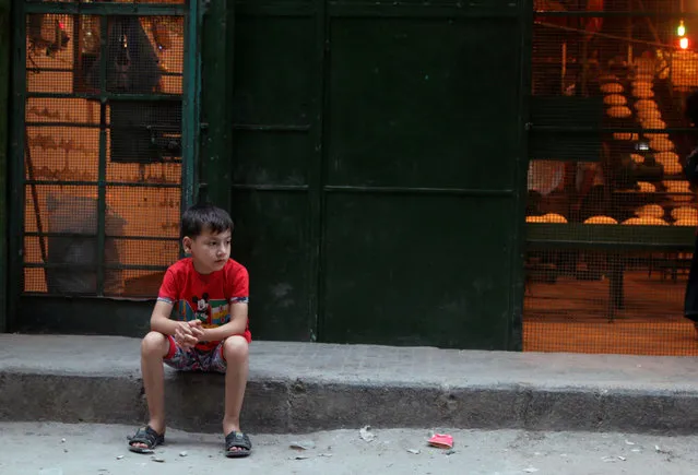 A boy sits outside a bakery in the rebel held al-Shaar neighbourhood of Aleppo, Syria July 14, 2016. (Photo by Abdalrhman Ismail/Reuters)