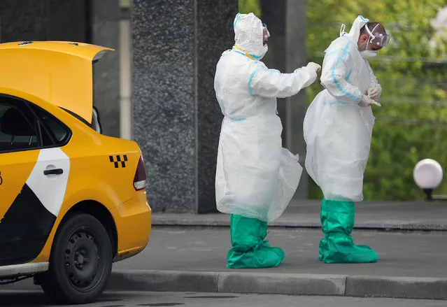 Police officers in protective gear are seen near a taxi car during the pandemic of the novel coronavirus disease (COVID-19) in Moscow, Russia on May 24, 2020. Since 30 March 2020, Moscow has been in lockdown, which has been extended till 31 May. On 12 May, wearing face masks in public became mandatory in the Russian capital. As of 24 May 2020, Russia has reported more than 344,000 confirmed cases of the novel coronavirus infection, with more than 163,000 confirmed cases in Moscow. (Photo by Mikhail Tereshchenko/TASS via Getty Images)