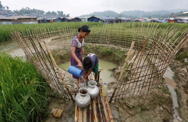 Rohingya refugee children collect water from a shallow well, dug from the sand outside their shelter at Uchiprang refugee camp near Cox’s Bazar, Bangladesh October 29, 2017. (Photo by Adnan Abidi/Reuters)