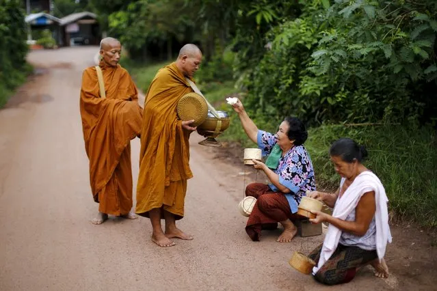 Buddhist monks receives rice from women early morning in a village outside Nong Khai, Thailand September 16, 2015. (Photo by Jorge Silva/Reuters)