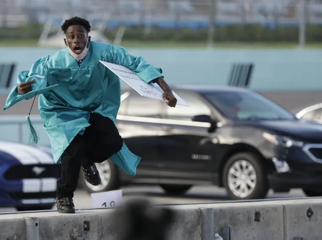 Richardson Fremond leaps over a wall as he runs to collect an award during a graduation ceremony for the senior class of Chambers High School at Homestead-Miami Speedway, Tuesday, June 23, 2020, in Homestead, Fla. Forty-one seniors graduated from the school and crossed the start-finish line to receive their diplomas, during the coronavirus pandemic. (Photo by Wilfredo Lee/AP Photo)