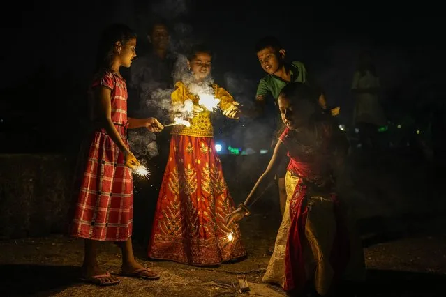 Children light the fire crackers during Diwali, the festival of lights in Mumbai, India, Monday, October 24, 2022. Indians across the country are celebrating Diwali, the Hindu festival that symbolizes the victory of light over darkness. (Photo by Rafiq Maqbool/AP Photo)