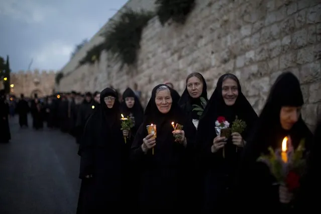 Orthodox nuns hold candles and flowers as they take part in a procession bringing an icon of Virgin Mary to the tomb where she is believed to be buried, through Jerusalem's Old City, Israel, 25 August 2016. Every year before the Feast of the Assumption, the icon is brought from the Church of the Holy Sepulcher to the tomb of the Virgin Mary to honor her Assumption. (Photo by Abir Sultan/EPA)
