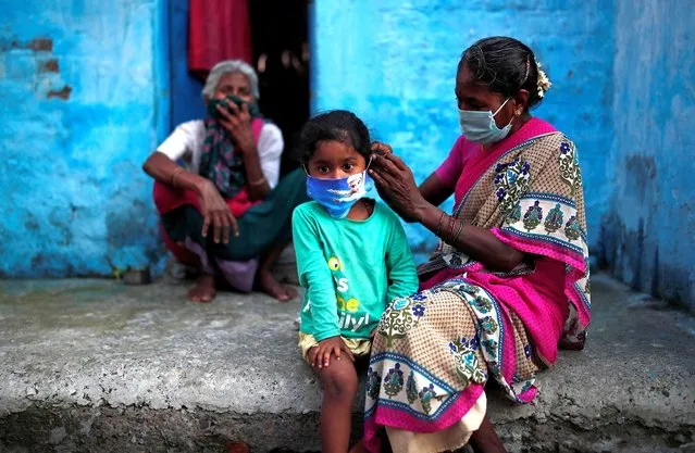 A woman wearing a protective face mask adjusts her daughter's face mask outside their house at a slum area, during an extended nationwide lockdown to slow the spreading of the coronavirus disease (COVID-19), in New Delhi, India, June 24, 2020. (Photo by Adnan Abidi/Reuters)