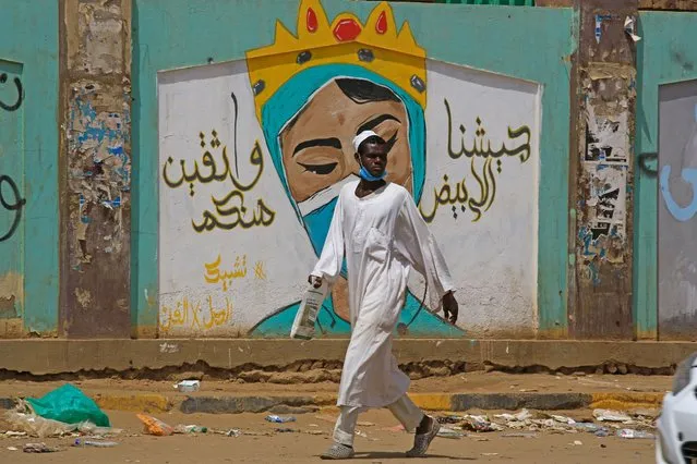 A man walks by a mural dedicated to health workers in the Sudanese capital's twin city of Omdurman on July 8, 2020, as the country eases lockdown measures following three months of tight restrictions due to the COVID-19 pandemic. (Photo by Ashraf Shazly/AFP Photo)