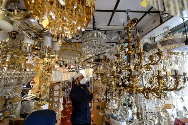 A shopkeeper cleans dust from a chandelier at a light shop in Dhaka on July 3, 2020. (Photo by Munir Uz Zaman/AFP Photo)