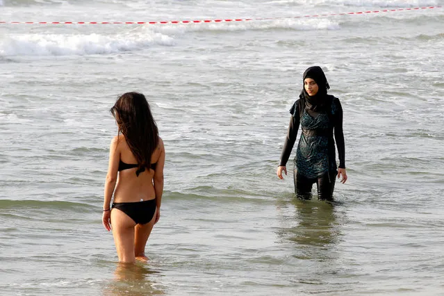 A Muslim woman wearing a Hijab stands next to a woman wearing a bikini in the Mediterranean Sea at a beach in Tel Aviv, Israel August 30, 2016. (Photo by Baz Ratner/Reuters)