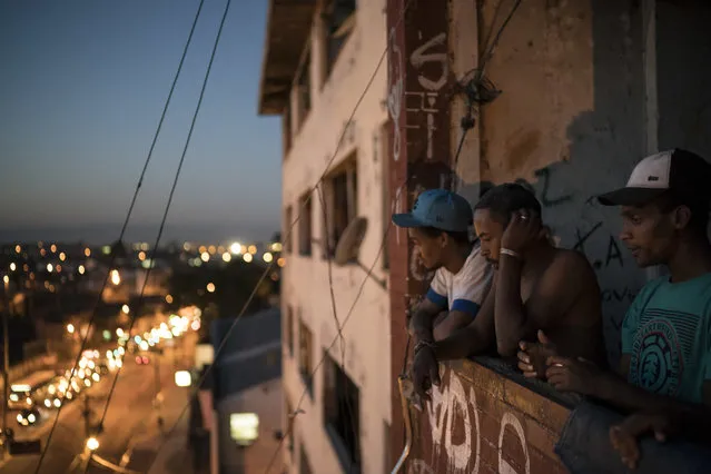 In this September 14, 2017 photo, residents look out from a balcony inside a squatter building that used to house the Brazilian Institute of Geography and Statistics (IBGE) in the Mangueira slum of Rio de Janeiro, Brazil. On the campaign trail, former President Luiz Inacio Lula da Silva promises both a return to better economic times and refocusing on the poor. (Photo by Felipe Dana/AP Photo)
