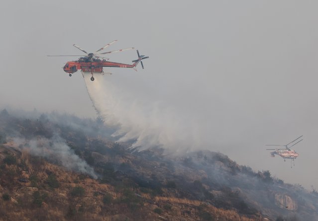 Helicopters extinguish wildfires by dropping water to a mountain in Ulsan, 305 kilometers southeast of Seoul, South Korea, 25 March 2025. (Photo by Yonhap/EPA/EFE)