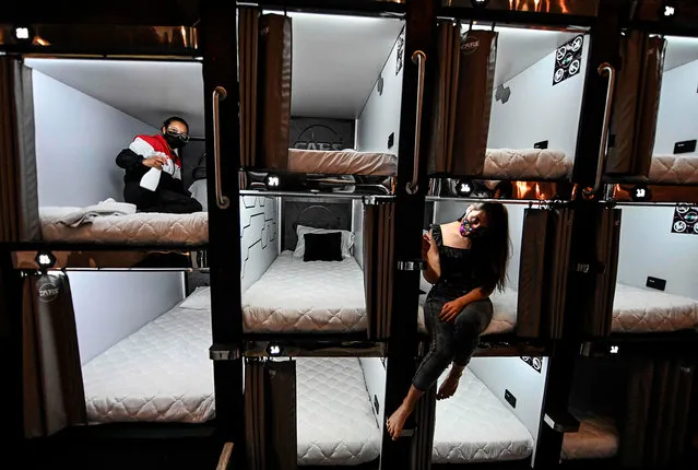 Women pose on pods at a capsule hotel in Bogota, Colombia on August 15, 2020. (Photo by Juan Barreto/AFP)