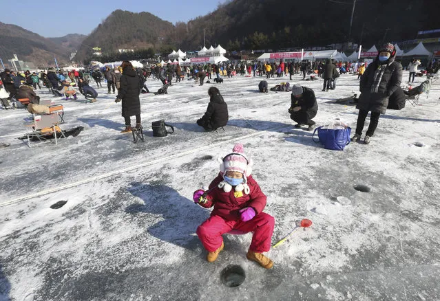 A girl casts a line through a hole drilled in the surface of a frozen river during a trout catching contest in Hwacheon, South Korea, Saturday, January 6, 2018. The contest is part of an annual ice festival which draws over 1,000,000 visitors every year. (Photo by Ahn Young-joon/AP Photo)