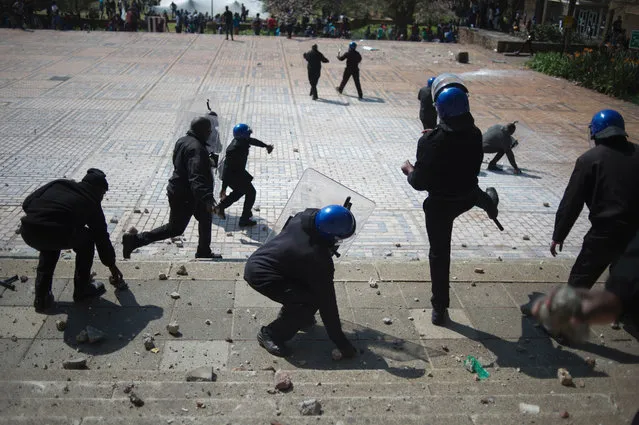 Security guards from the University of the Witwatersrand pelt with stones students during clashes at a demonstration against university fee hikes, on September 20, 2016 in Johannesburg. South African students and campus security guards clashed in Johannesburg on September 20, hurling rocks at each other as demonstrations over higher fees turned violent, a day after the government said that next year's fee hikes would be capped at eight percent, prompting protests on several campuses across the country. Student groups last year secured a zero percent fee increase after weeks of demonstrations rocked the government, and had demanded a freeze on all fees until a commission into university funding was complete. (Photo by Mujahid Safodien/AFP Photo)