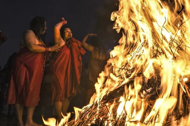 Hindu devotees warm themselves around bonfires after bathing in the Shali river during the Swasthani Brata Katha festival, marked with an auspicious bathing hoping for a prosperous life and conjugal happiness, in Sankhu on the outskirts of Kathmandu on January 6, 2023. (Photo by Prakash Mathema/AFP Photo)