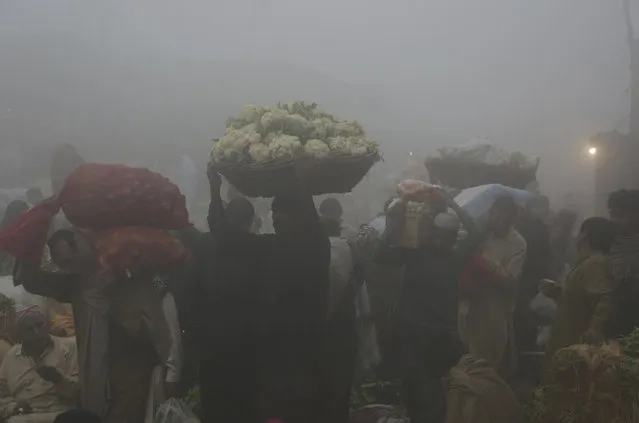 Laborers work at a produce market covered in heavy smog in Lahore, Pakistan, Saturday, November 11, 2017. (Photo by K.M. Chaudary/AP Photo)