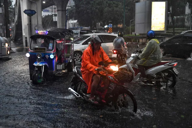 Motorists drive through a flooded road during a heavy rain in Bangkok on September 23, 2020. (Photo by Lillian Suwanrumpha/AFP Photo)