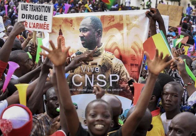 People hold a banner showing Col. Assimi Goita, leader of the junta which is now running Mali and calls itself the National Committee for the Salvation of the People, as they demonstrate to show support for the junta in the capital Bamako, Mali, Tuesday, September 8, 2020. Placard at left in French reads “An army-led transition”. (Photo by AP Photo/Stringer)