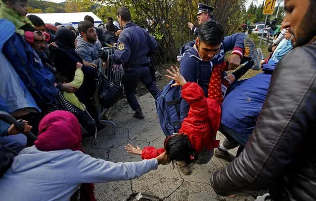 Migrants hold a child as a crowd of migrants attempts to break through a cordon in front of a makeshift camp near the Austrian border in Sentilj, Slovenia October 20, 2015. (Photo by Leonhard Foeger/Reuters)