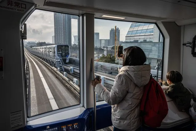 People look out of the window on a train in Tokyo on January 24, 2023. (Photo by Yuichi Yamazaki/AFP Photo)