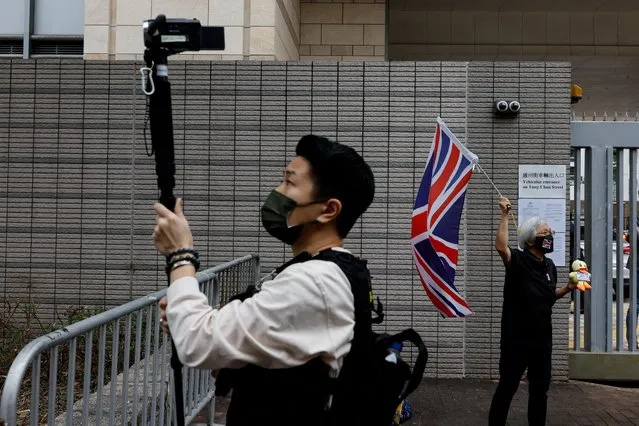 A member of the police records video as a supporter waves a Union Jack flag outside the West Kowloon Magistrates' Courts building during the hearing of the 47 pro-democracy activists charged with conspiracy to commit subversion under the national security law, in Hong Kong, China on February 6, 2023. (Photo by Tyrone Siu/Reuters)