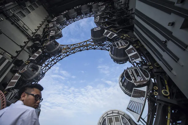 An employee stands near passenger pods at the Golden Reel ferris wheel at Studio City casino resort, developed by Melco Crown Entertainment Ltd., in Macau, China, on Tuesday, October 27, 2015. Studio City is the latest test of the former Portuguese colony's ability to attract visitors wanting to play on more than gaming tables and slot machines. (Photo by Justin Chin/Bloomberg)