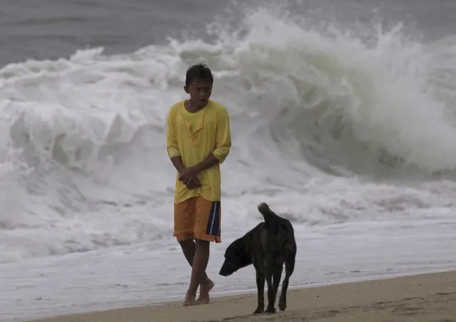 A boy with his pet dog walks beside high waves after strong winds and heavy rains brought on by Typhoon Hagupit battered Laiya town, San Juan city, Batangas province, south of Manila, December 9, 2014. (Photo by Romeo Ranoco/Reuters)