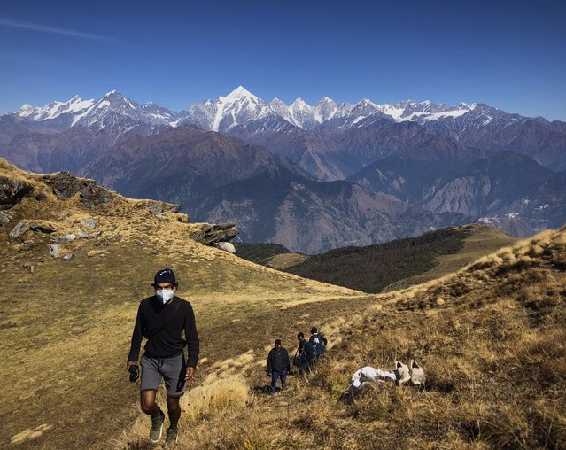 People wearing face masks trek up to Khalia top as snow clad Himalayan ranges of Panchchuli mountains are seen behind near Munsiyari in the Indian state of Uttarakhand, Thursday October 29, 2020. (Photo by Manish Swarup/AP Photo)