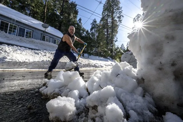 Michael Romero clears snow in front of his home, where his three vehicles are buried under heavy snowfall, in Crestline, Calif., Friday, March 3, 2023. (Photo by Watchara Phomicinda/The Orange County Register via AP Photo)