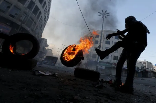 A Palestinian protester pushes a burning tyre during clashes with Israeli troops in the West Bank city of Hebron October 31, 2015. (Photo by Ammar Awad/Reuters)