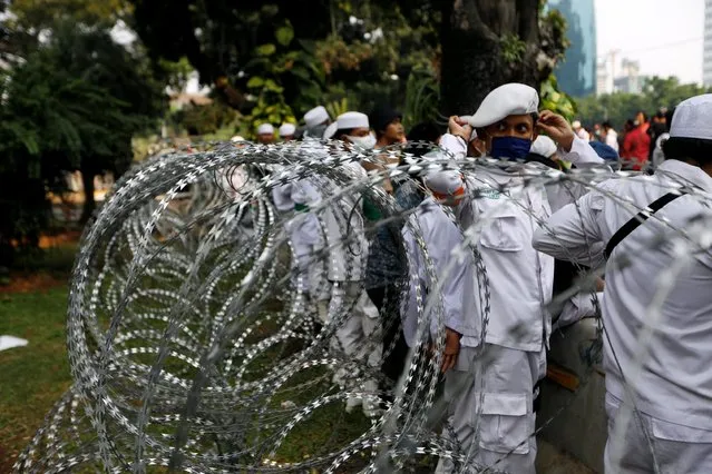 A member of an Indonesian Islamist group wearing a protective face mask stands near a barbwire during a protest against the new so-called omnibus law near the National Monument (Monas) in Jakarta, Indonesia, October 13, 2020. (Photo by Willy Kurniawan/Reuters)