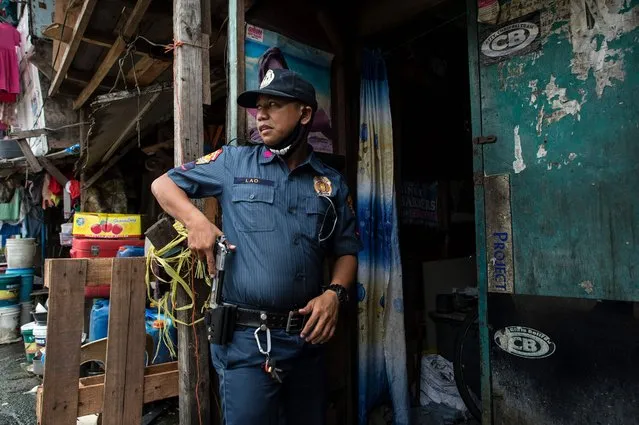 A police officers draws his gun as he is about to enter a house during an “Oplan Tokhang” or house-to-house campaign on illegal drugs at an informal settlers community in Manila on October 6, 2016. Philippine President Rodrigo Duterte told all his critics to “go to hell” on October 6, as he renewed his threats to kill, after a poll showed Filipinos overwhelmingly endorsed his deadly war on crime. (Photo by Noel Celis/AFP Photo)