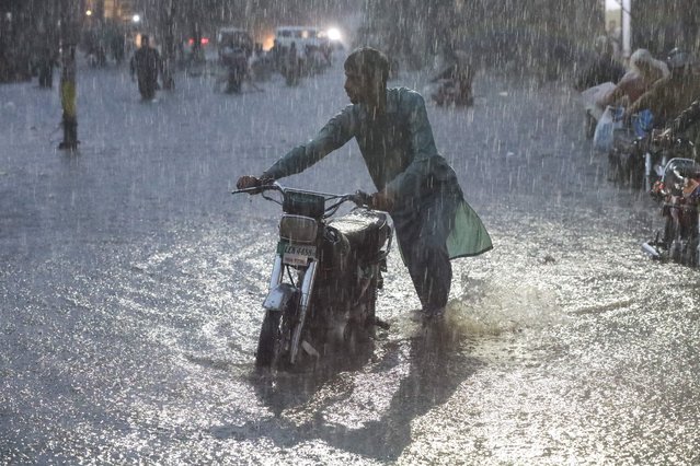 A man pushes his motorbike as he wades through a flooded road amid rain in Lahore, Pakistan, on September 8, 2025. (Photo by Mohsin Raza/Reuters)