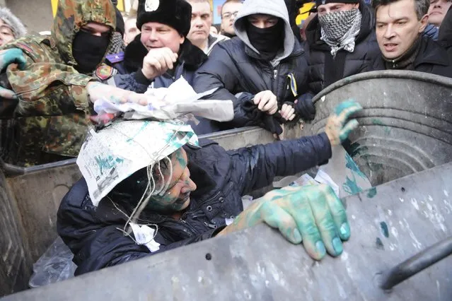 Vladimir Skorobagach, deputy of the Kharliv city council, reacts after being thrown by activists into a garbage container during a protest for the resignation of the Kharkiv's mayor Gennady Kernes outside the city council in Kharkiv, December 24, 2014. (Photo by Reuters/Stringer)