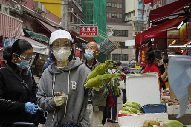 People wearing face masks to protect against the spread of the coronavirus shop at a local market in Hong Kong, Tuesday, December 8, 2020. Hong Kong leader Carrie Lam said social distancing measures will be tightened as cases of the coronavirus continue to surge, with a ban on nighttime dining and more businesses ordered to close. (Photo by Kin Cheung/AP Photo)